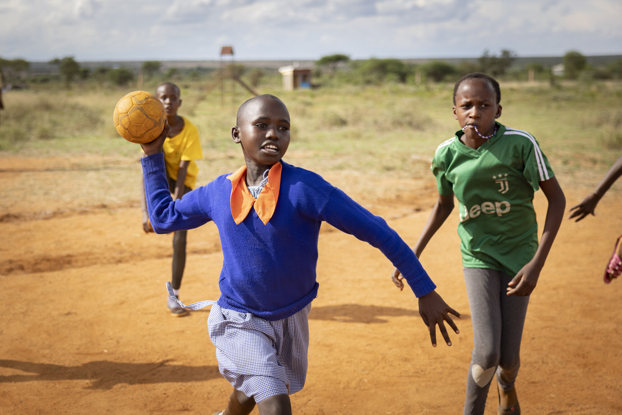 Girls play handball together at a primary school supported by ChildFund in Kajiado County, Kenya. This school has been supported by ChildFund through its local partner, Mount Kilimanjaro Child Development Programme, for more than two decades. ChildFund currently works in the school by facilitating the Child Rights Club, providing supplementary food for students and running tree planting and kitchen gardens programs. Perhaps most crucially, ChildFund constructed a school dormitory nearly three years ago as a safe place for girls to learn away from the pressures of the surrounding community.

Kajiado County, Kenya, East Africa. March 2024. Photo by Jake Lyell for ChildFund.